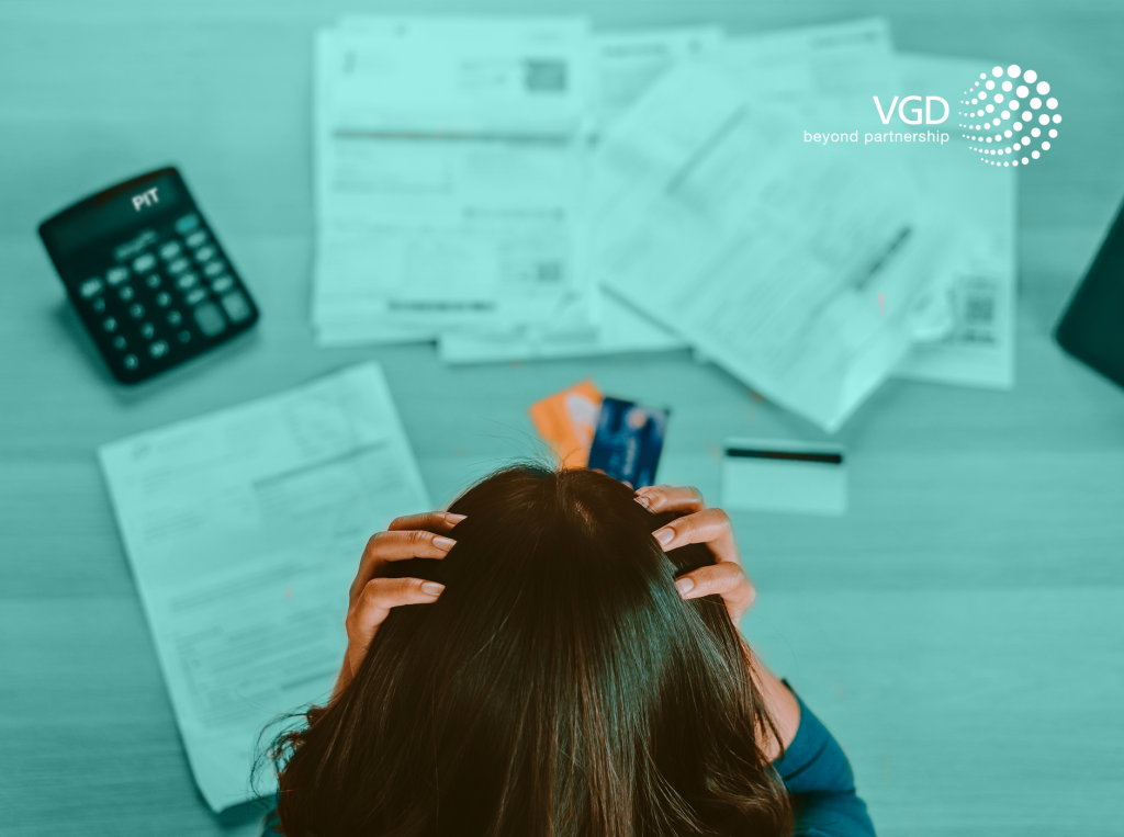 women keeping her head in hands sitting in front of documents and calculator, cyan background