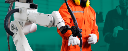 a production robot controlled by a man in a yellow helmet and orange scruffs