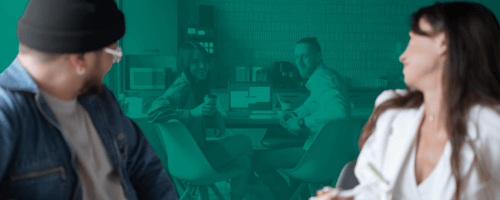 a woman and a man are sitting in the kitchen in the office eating snacks and drinking drinks smiling