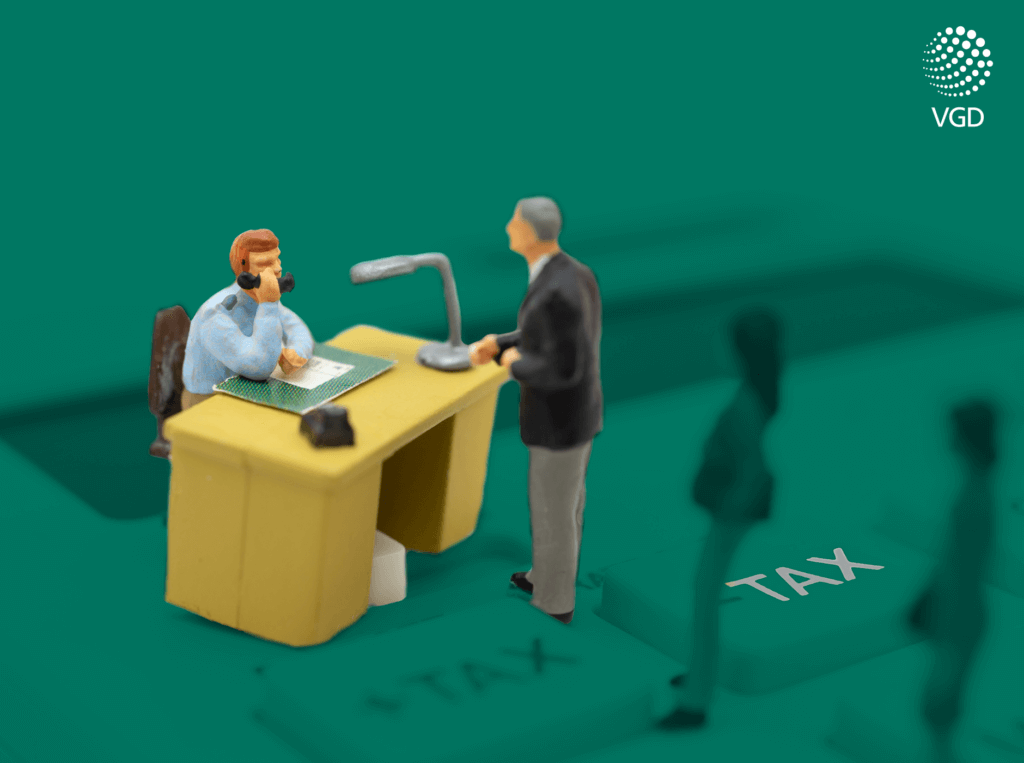 miniaturowy mężczyzna stoi przy biurku w urzędzie skarbowym i rozmawia z urzędnikiem na temat podatków