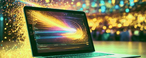 na biurku jest postawiony laptop. Na ekranie laptopa odbywa się proces, któremu towarzyszą iskry i błyskotki
